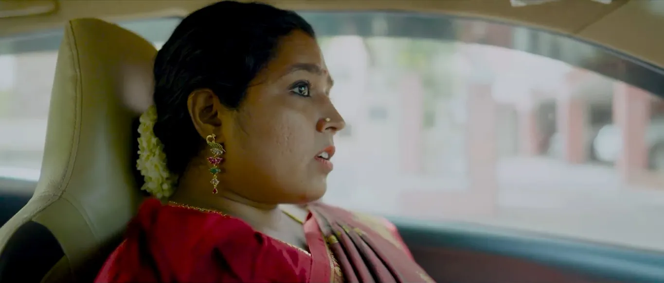 A woman in a red saree in the back seat of a car, from Akkarai