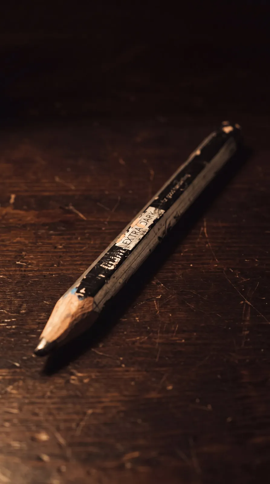 A worn pencil on a dark wooden desk, from Apsara